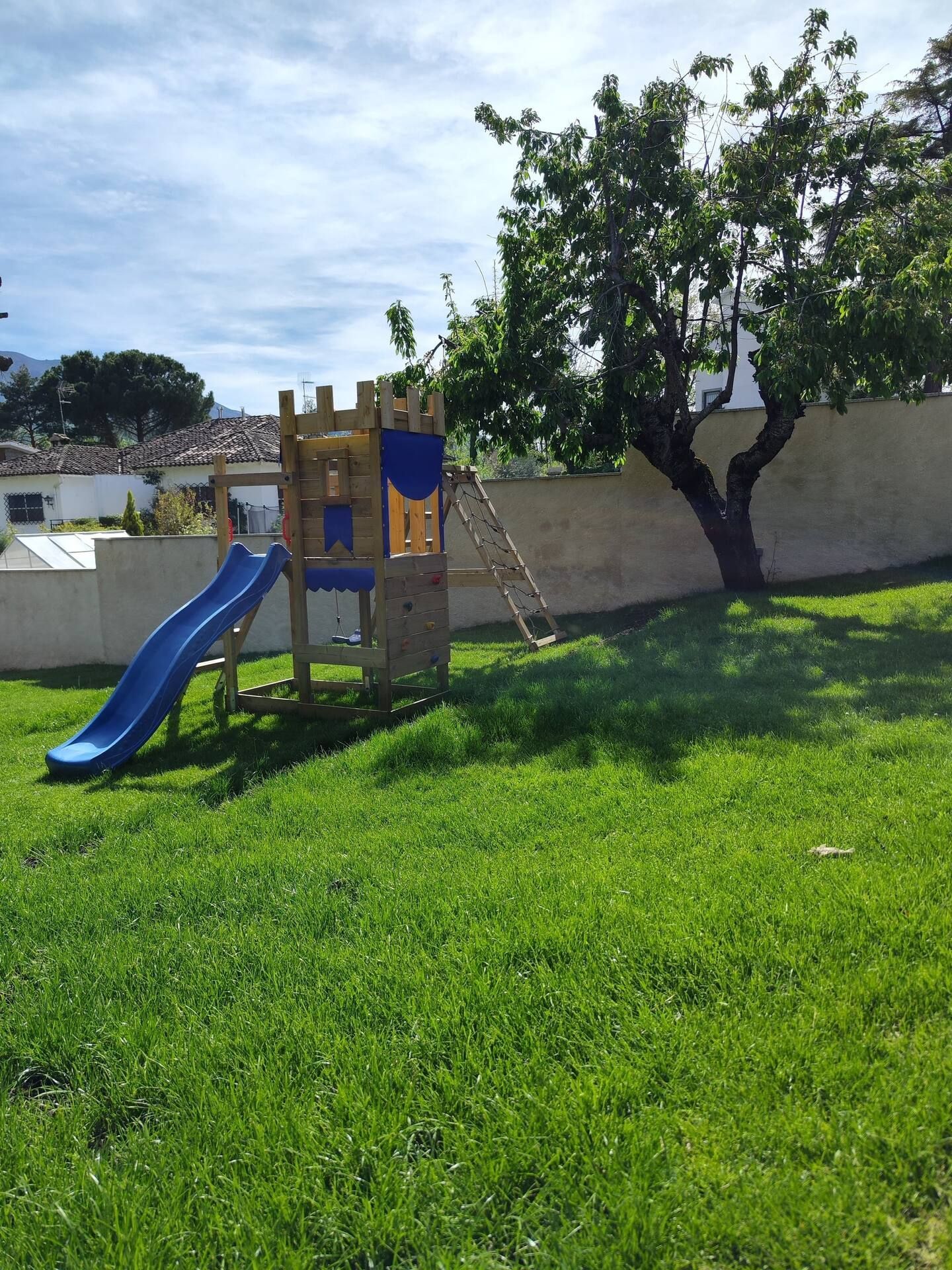 Un parque infantil con tobogán y columpios en el césped.