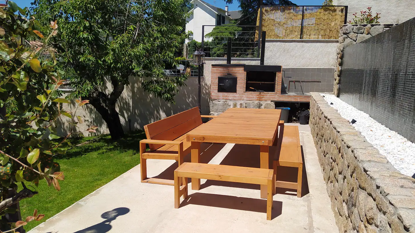 Una mesa de picnic de madera y bancos en un patio trasero.