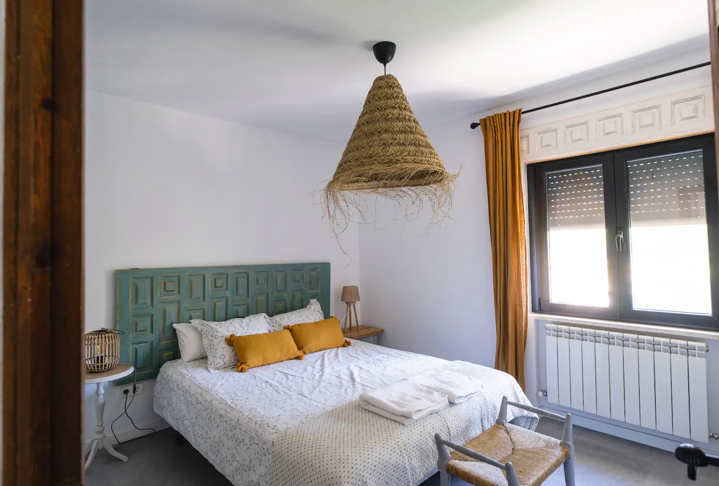 Un dormitorio con una cama, silla, mesa y ventana.