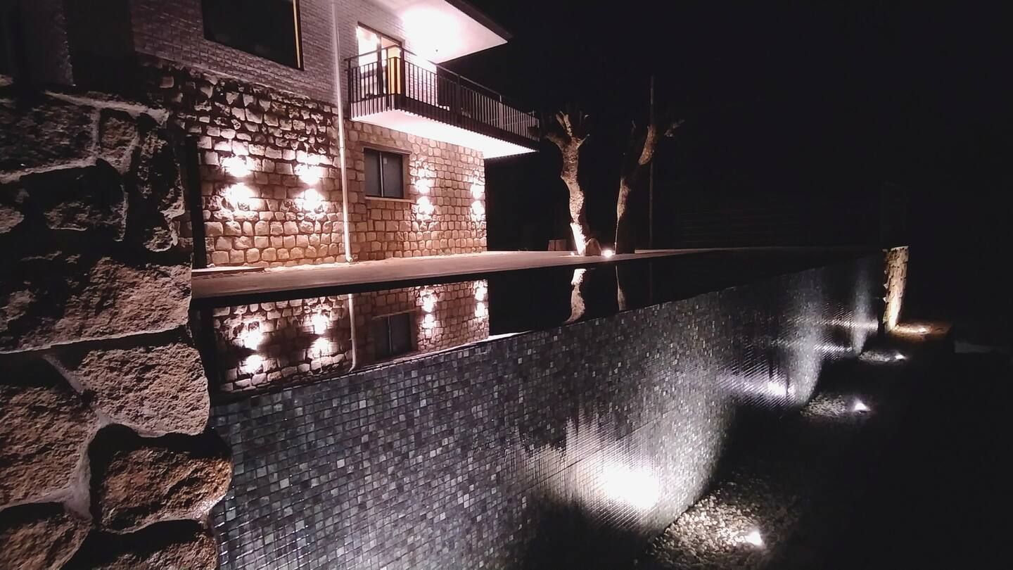 Una casa con piscina delante de ella por la noche.