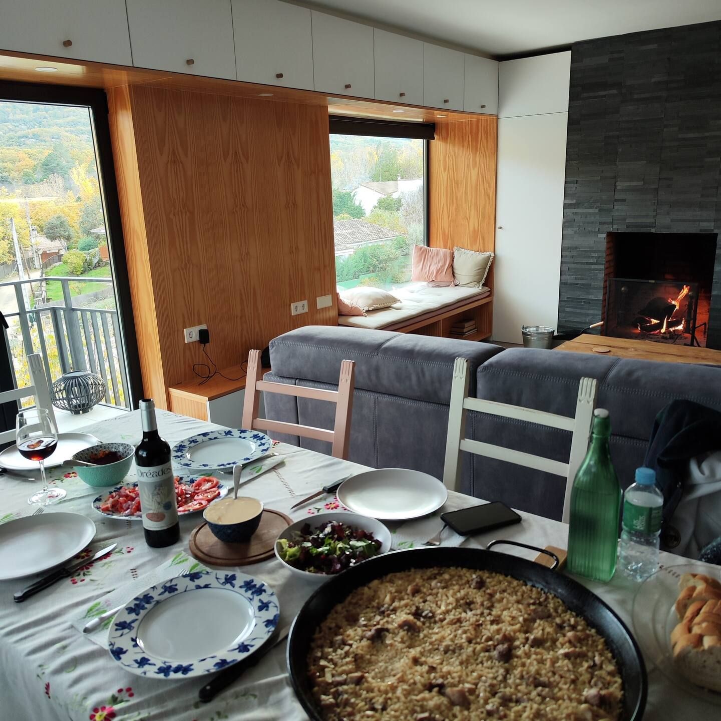 Una mesa con platos de comida y una botella de vino.