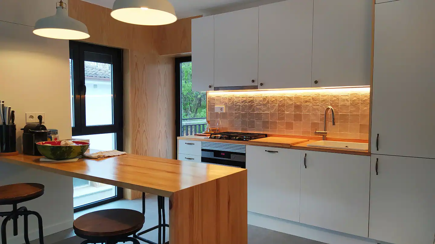 Una cocina con muebles blancos y una mesa de madera.