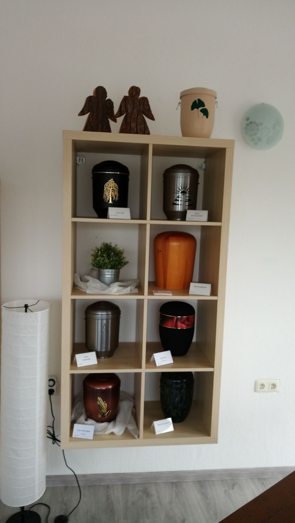 Auslage von Urnen mit Verzierungen in einem Regal aus Holz