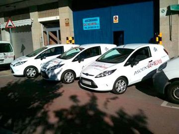 Una fila de furgonetas blancas estacionadas frente a un edificio.