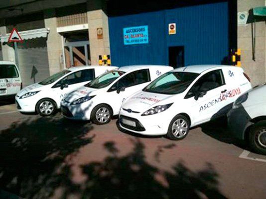 Una fila de furgonetas blancas estacionadas frente a un edificio.