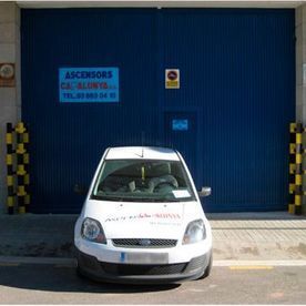 Un coche blanco está aparcado delante de una puerta de garaje azul.
