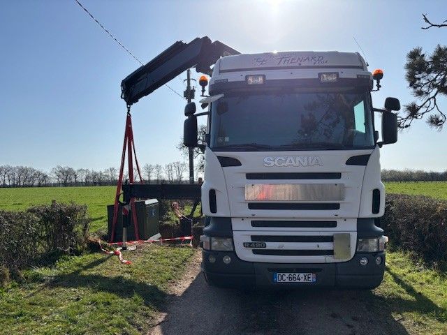 Une dépanneuse soulève un camion Scania blanc au bord d'une route de campagne