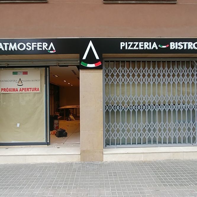 Exterior de una pizzería y bistró con una puerta metálica cerrada. El cartel tiene una bandera italiana y dice