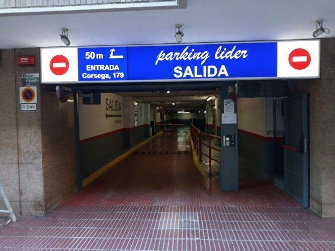 Entrada al "Parking Líder", señalizada como "Salida". Letrero azul con texto blanco y señales de stop rojas.