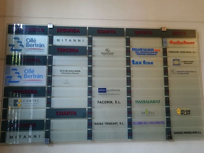 Tablero de directorio de la oficina con nombres de empresas, incluidos "Olle Bertran", "MITANNI" y "Tax Free".