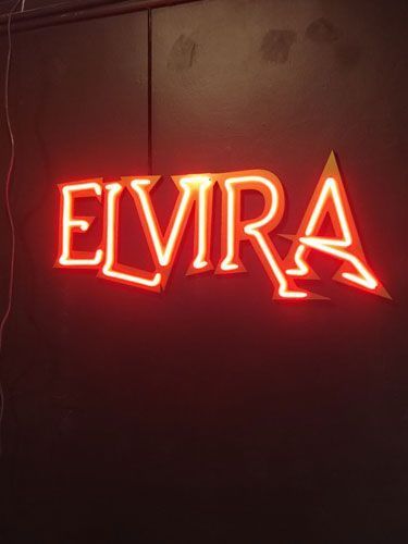 Rótulo de neón del nombre "ELVIRA" en color rojo sobre fondo oscuro.