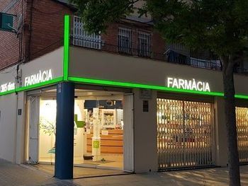 Fachada de farmacia con moldura verde y cartel 