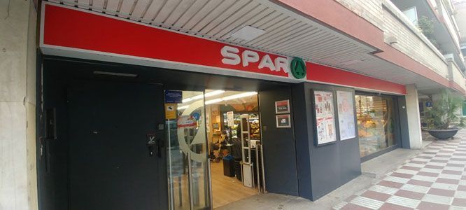 Entrada a un supermercado SPAR, señalización roja, puertas de cristal, acera, calle.