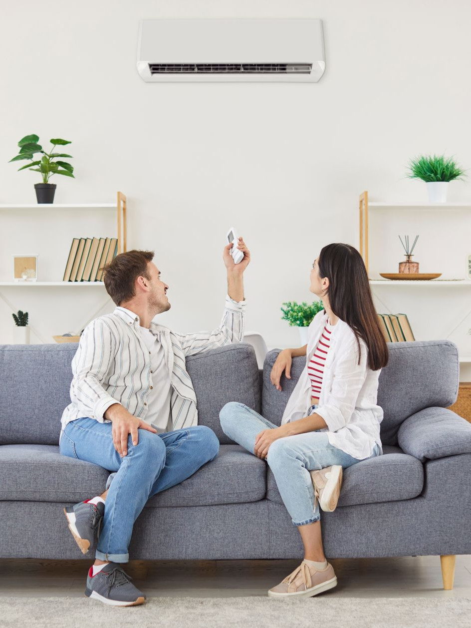 Un couple est assis sur un canapé et utilise la télécommande d'un climatiseur.