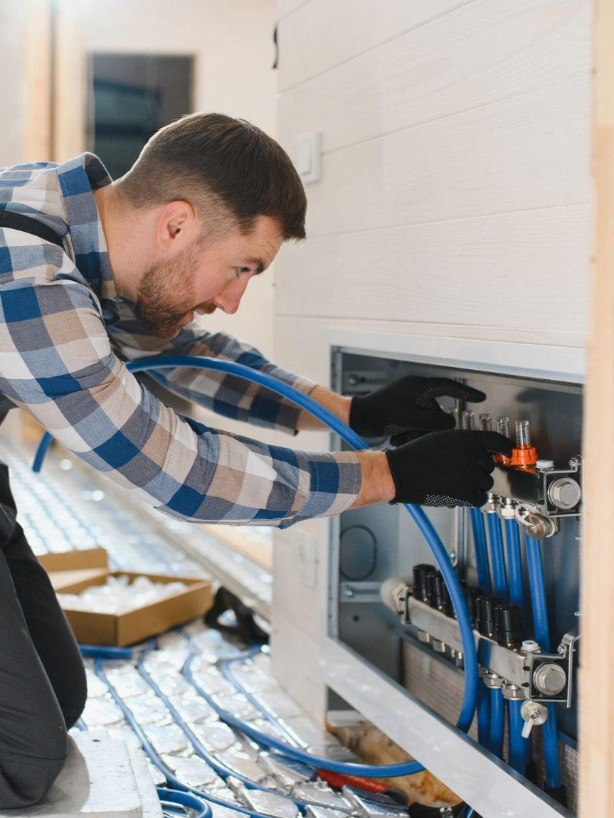 Un technicien contrôle le fonctionnement des vannes d'un plancher chauffant.