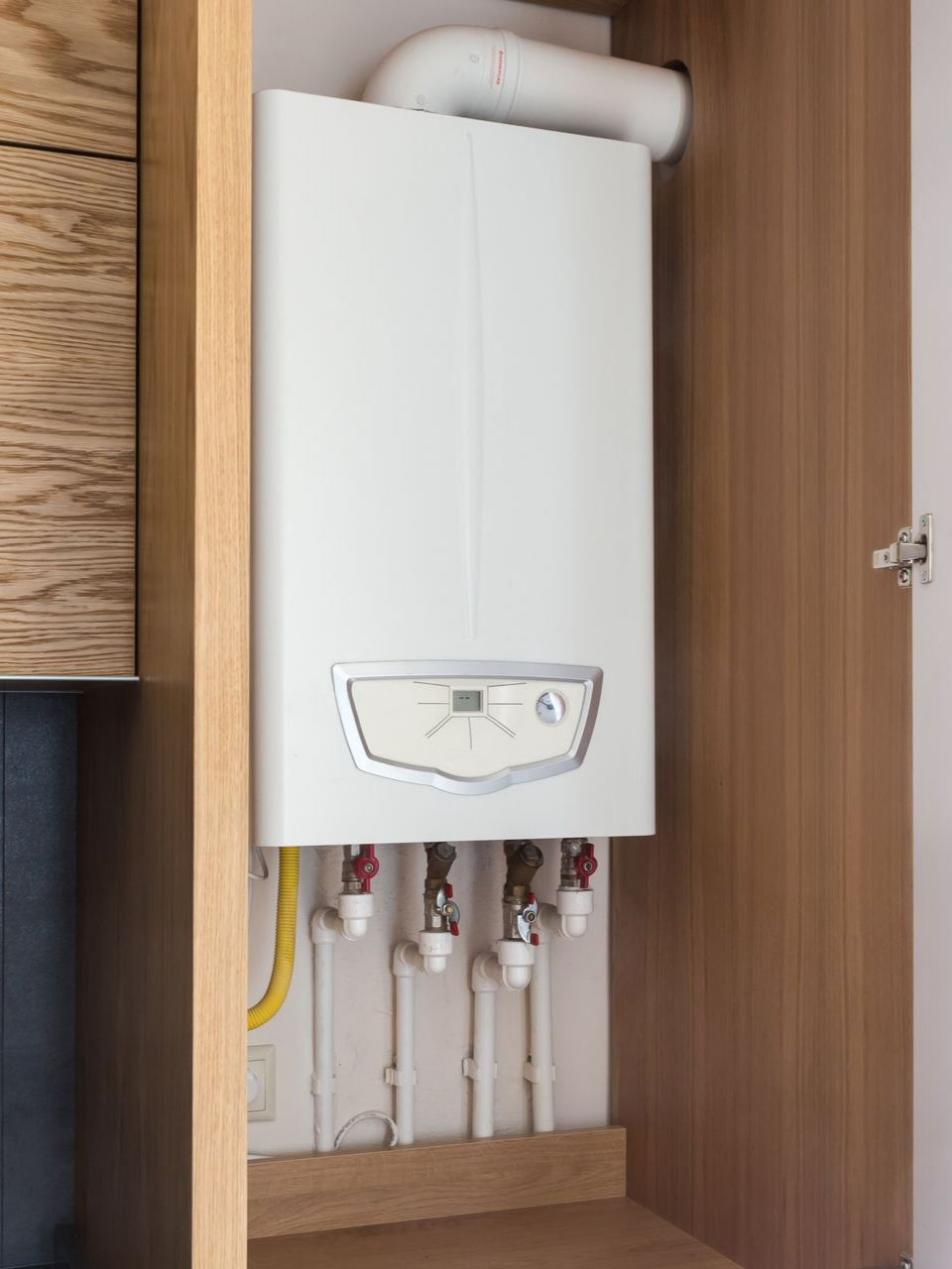 Chaudière à gaz à l'intérieur d'un meuble en bois.