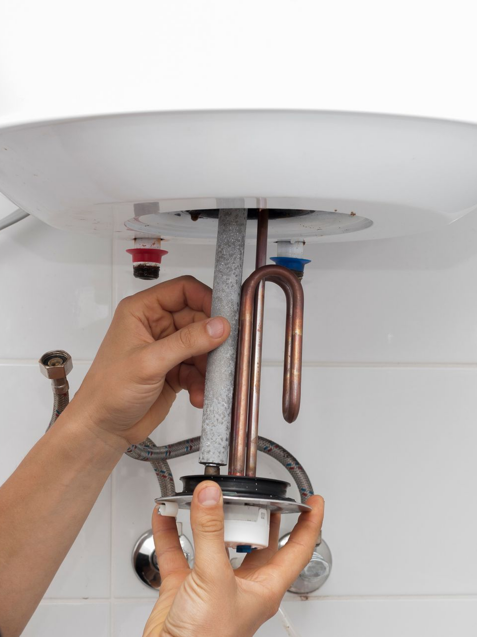 Une personne remplace la résistance d'un chauffe-eau.