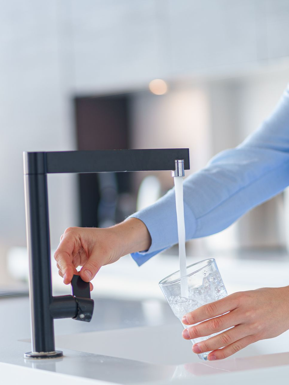 Une personne remplit un verre d'eau à un robinet.