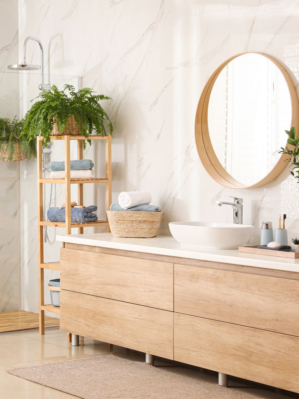 Salle de bains moderne avec un meuble-vasque en bois, un miroir rond et des étagères avec des serviettes et plantes.