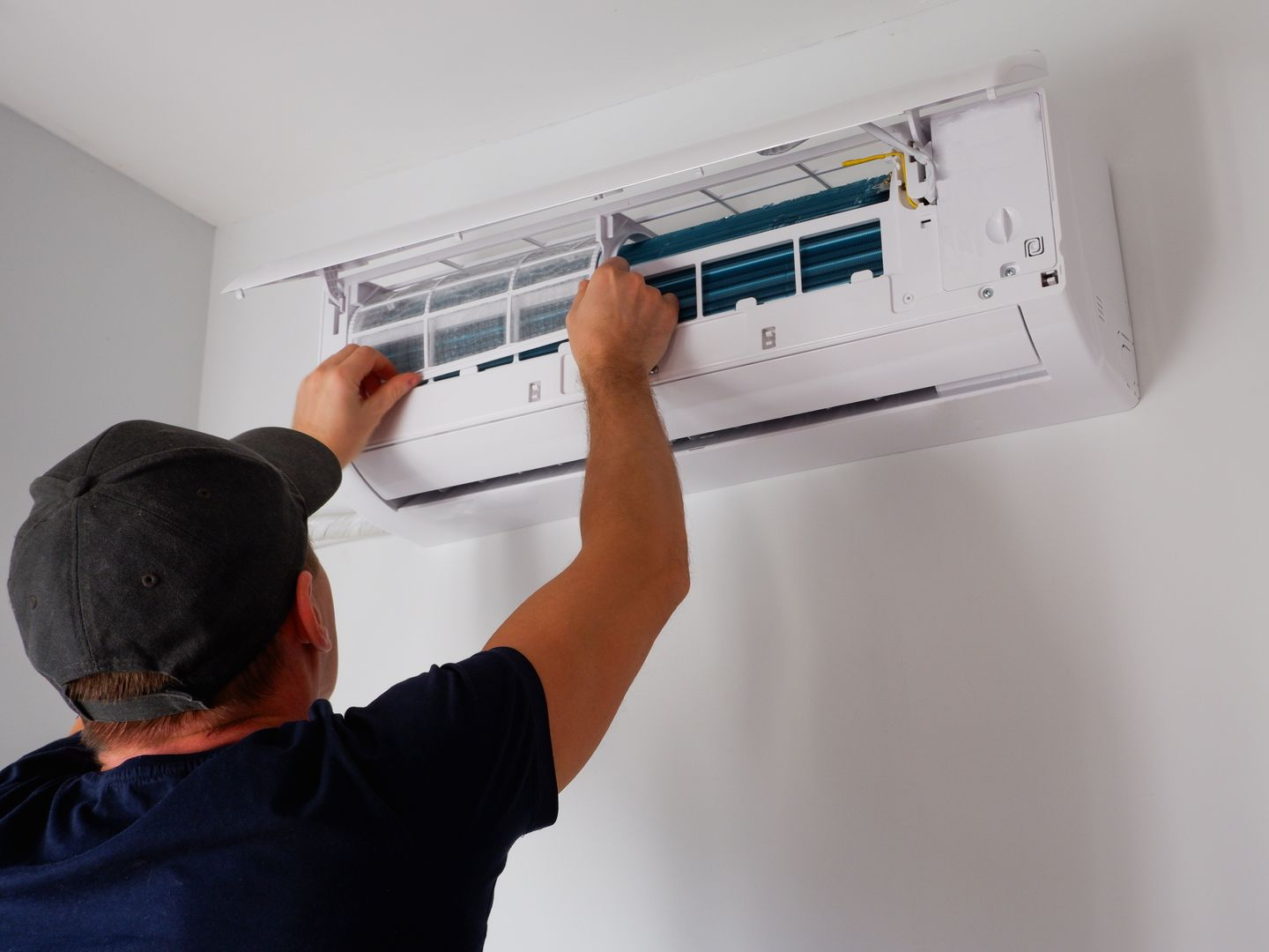 Une personne nettoie le filtre d'un climatiseur.