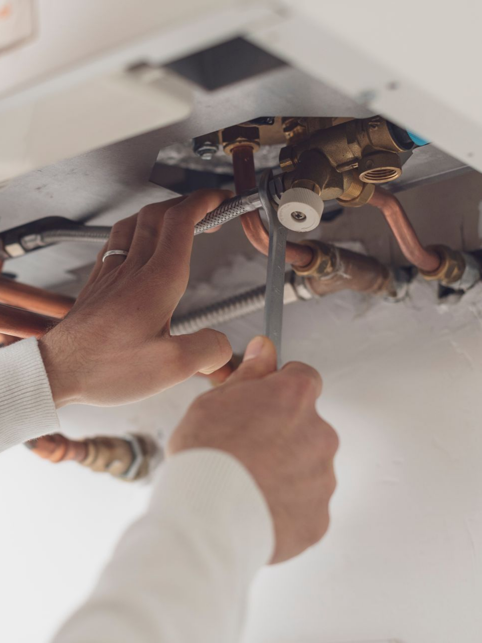 Une personne utilise une clé pour travailler sur des tuyaux reliés à une chaudière.