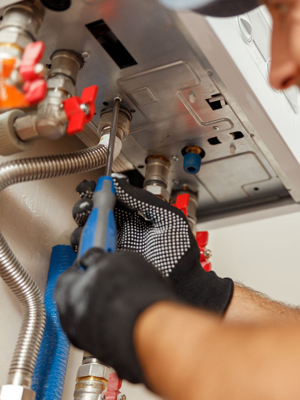 Une personne utilise un tournevis pour travailler sur une chaudière.