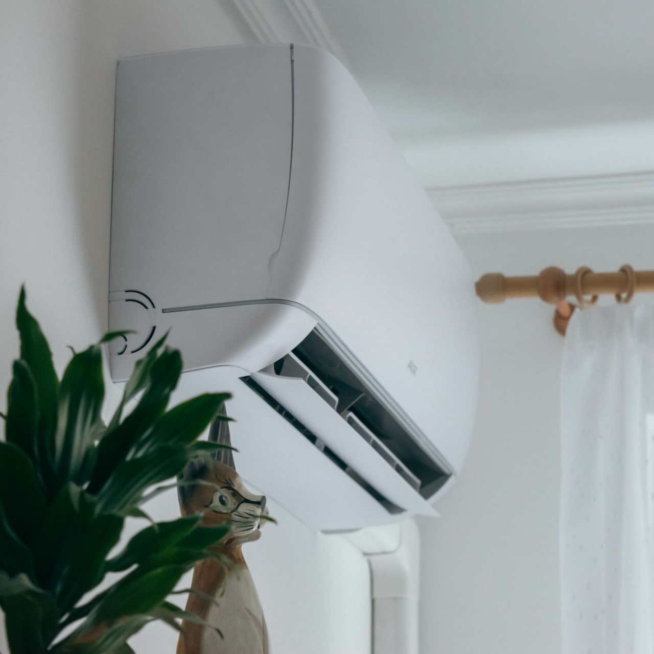 Unité de climatisation blanche fixée sur un mur blanc.