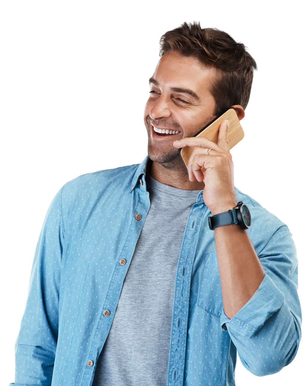 Un homme souriant, habillé d'une chemise bleue, qui discute au téléphone.