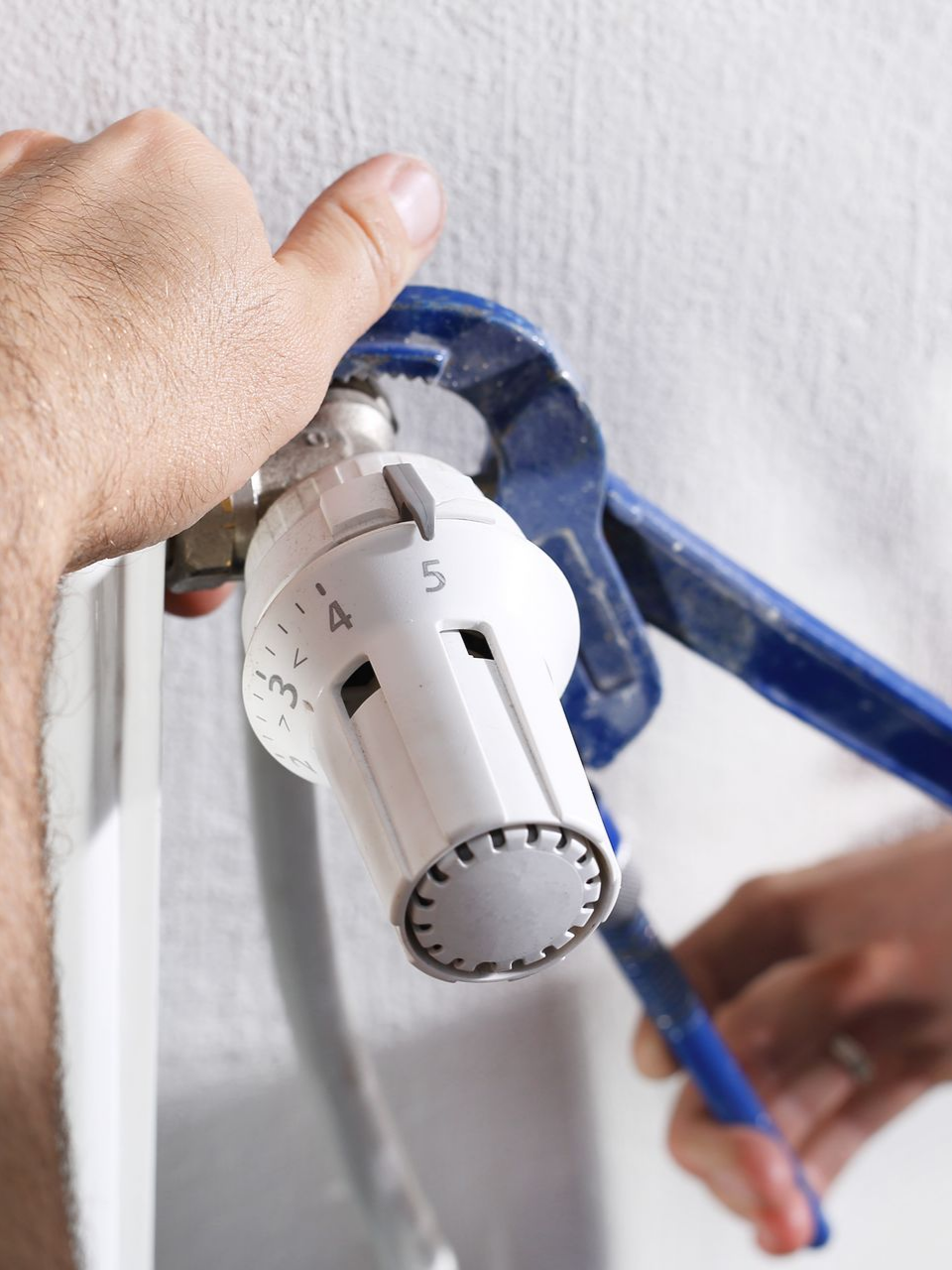 Personne utilisant une clé pour régler un robinet de radiateur.
