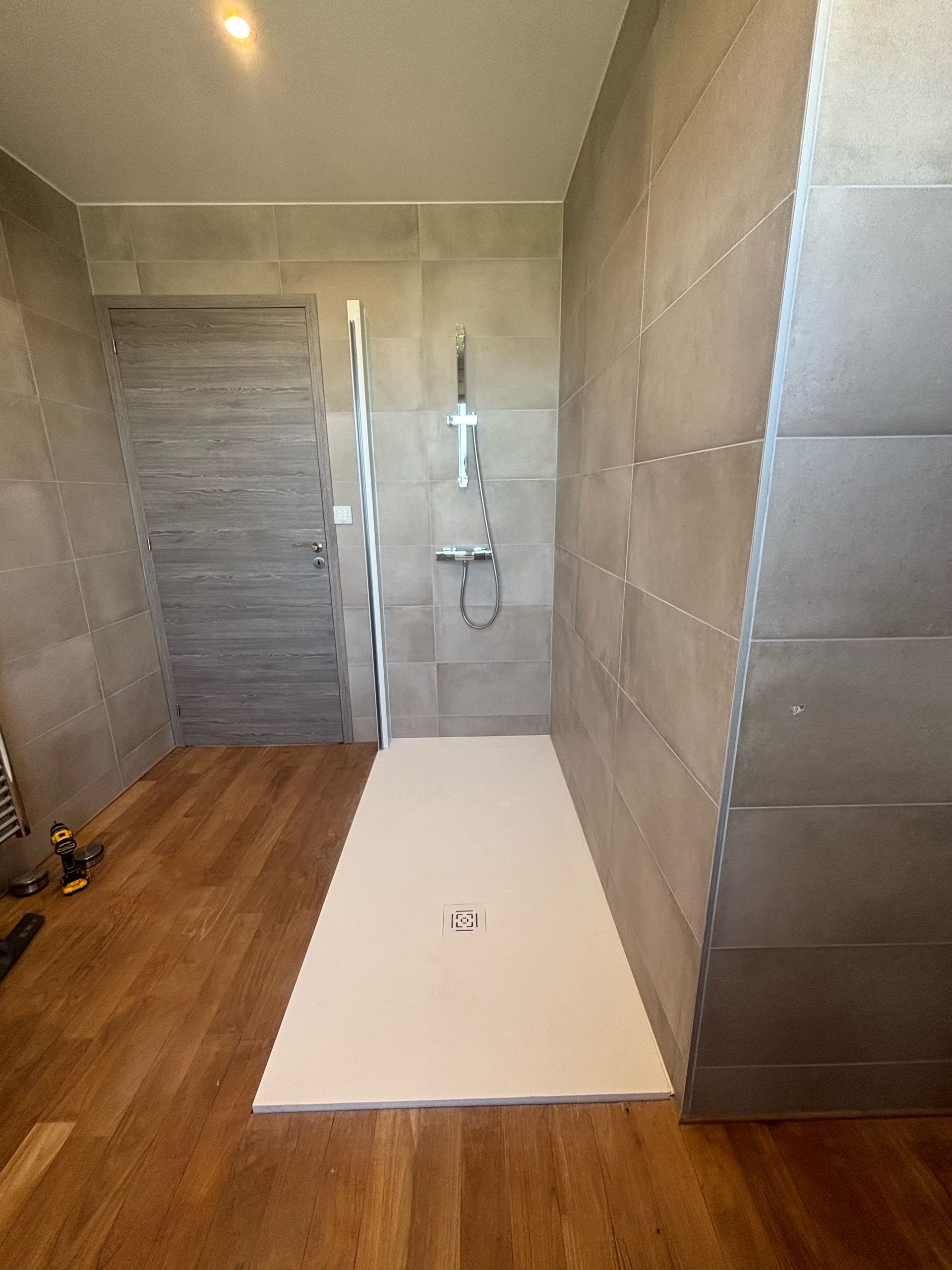 Salle de bains avec receveur de douche blanc et paroi en verre.