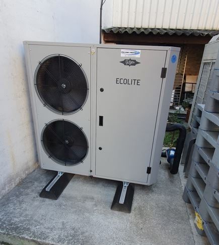 Unité de pompe à chaleur Ecolite grise à l'extérieur, avec deux ventilateurs, sur une dalle de béton.