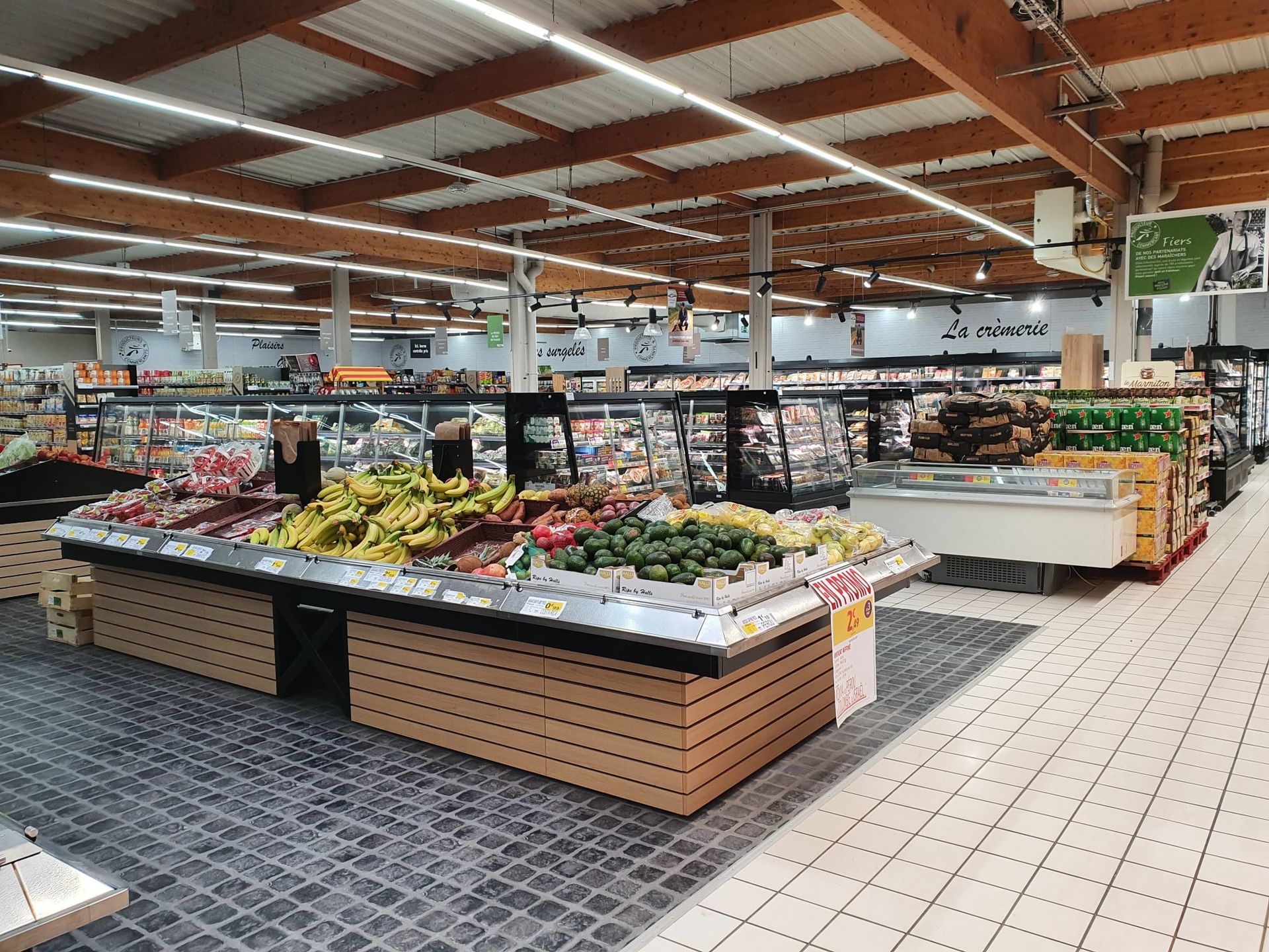 Rayon fruits et légumes d'un supermarché bien éclairé ; fruits et légumes exposés.