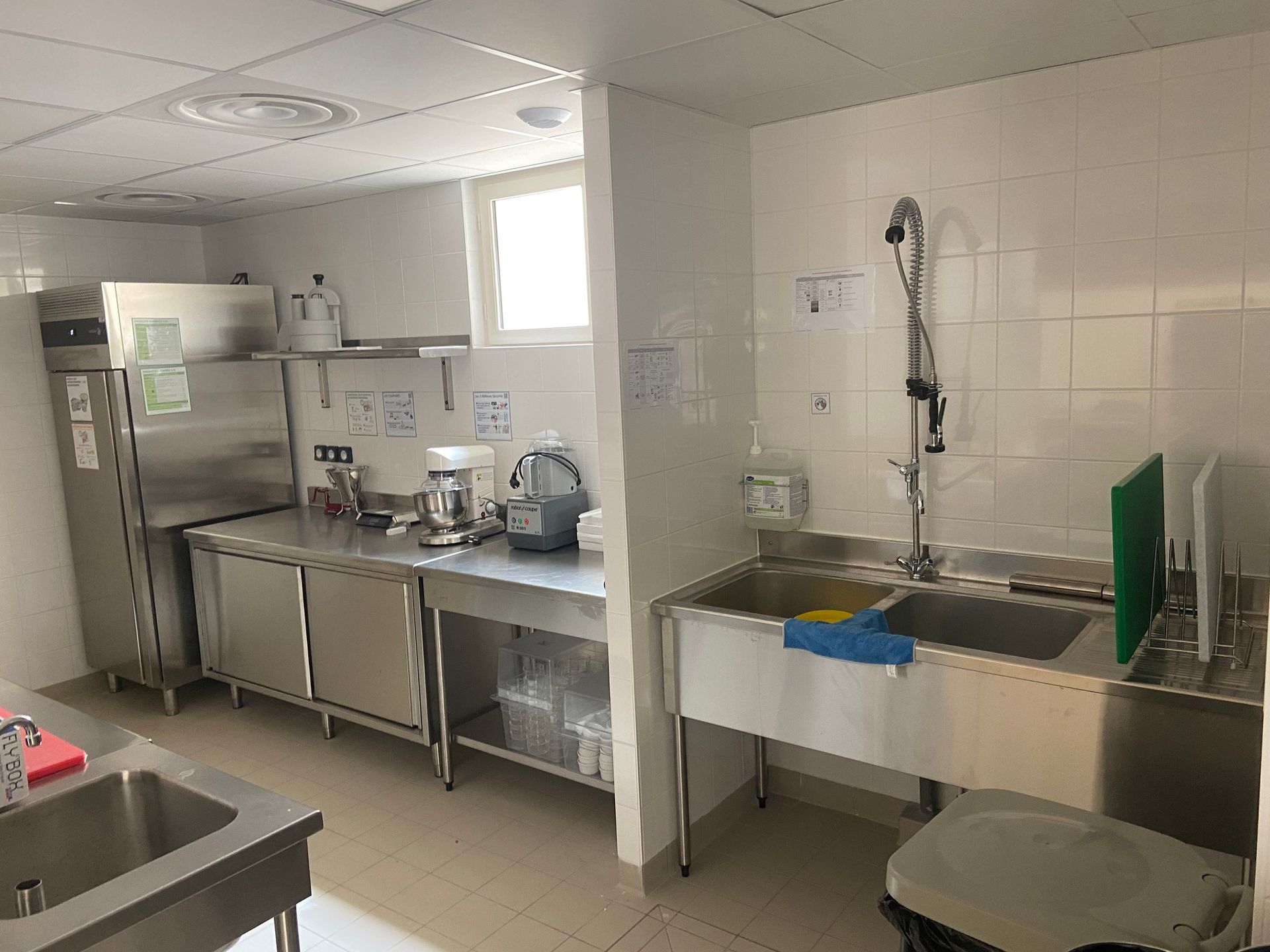 Cuisine commerciale équipée d'appareils électroménagers en acier inoxydable, d'un évier et de plans de travail.