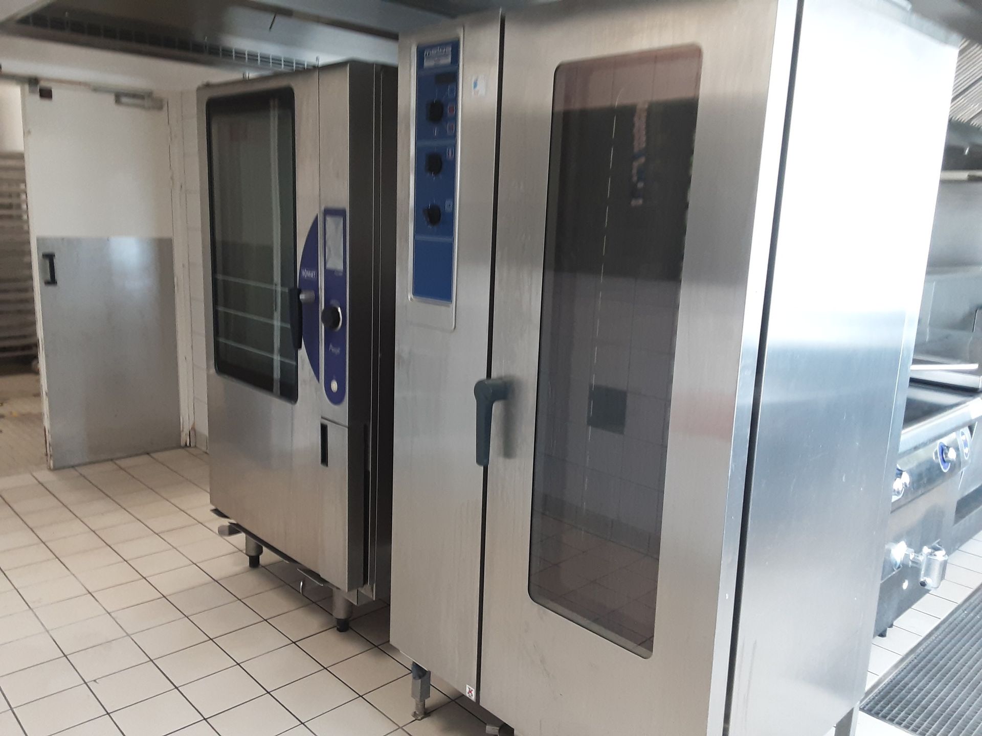 Deux fours commerciaux en acier inoxydable dans une cuisine au sol carrelé.