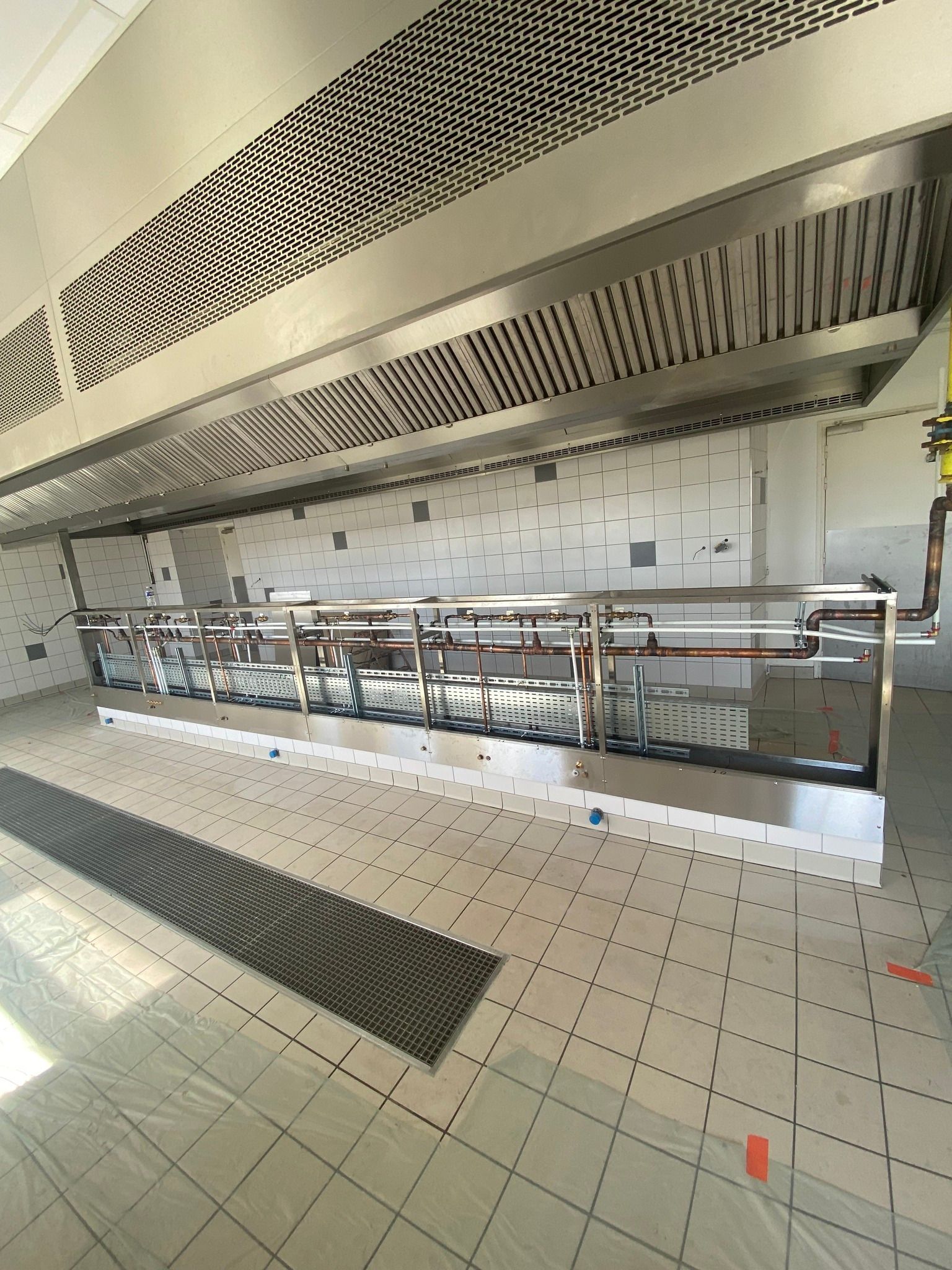 Cuisine en acier inoxydable avec hotte aspirante et comptoirs.