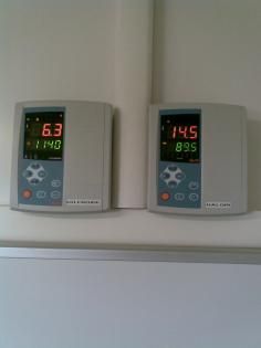 Deux écrans numériques muraux affichent des données numériques, probablement des relevés d'instruments.