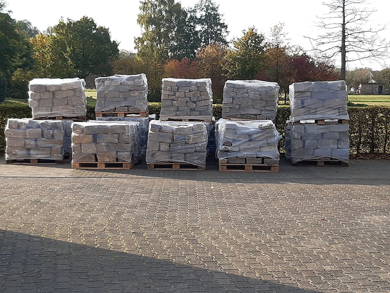 Auf einem Parkplatz sind Paletten mit Ziegeln übereinander gestapelt