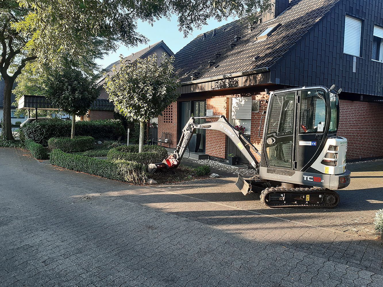 Vor einem Haus parkt ein kleiner Bagger.