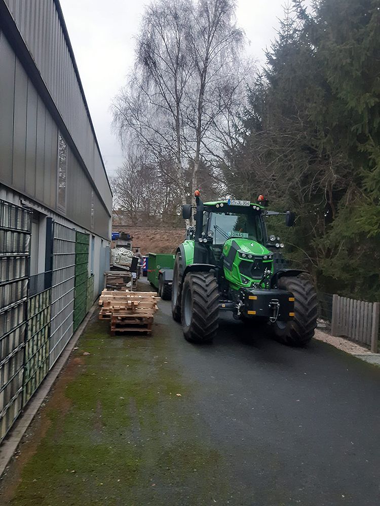 Ein grüner Traktor steht vor einem Gebäude.