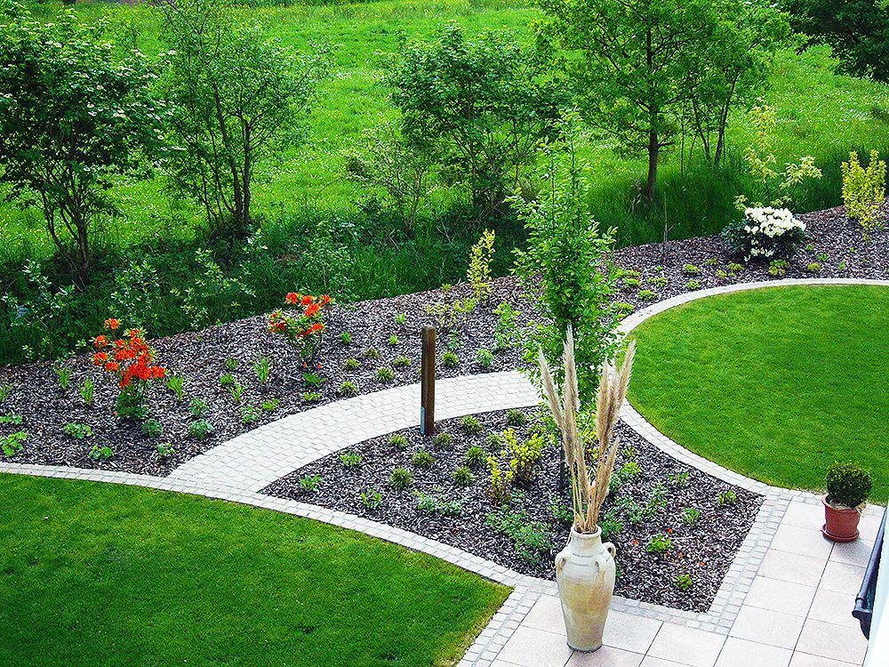 Eine große Vase steht inmitten eines üppig grünen Gartens.