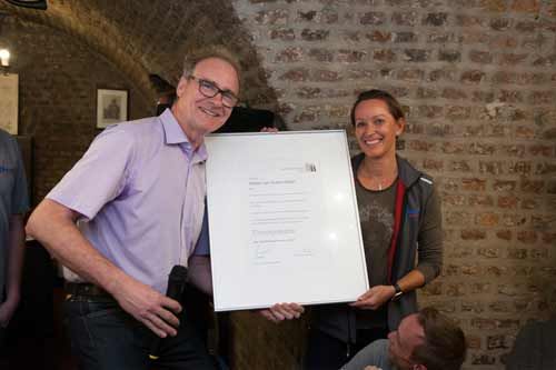 Ein Mann und eine Frau halten eine weiße Tafel vor einer Backsteinwand.