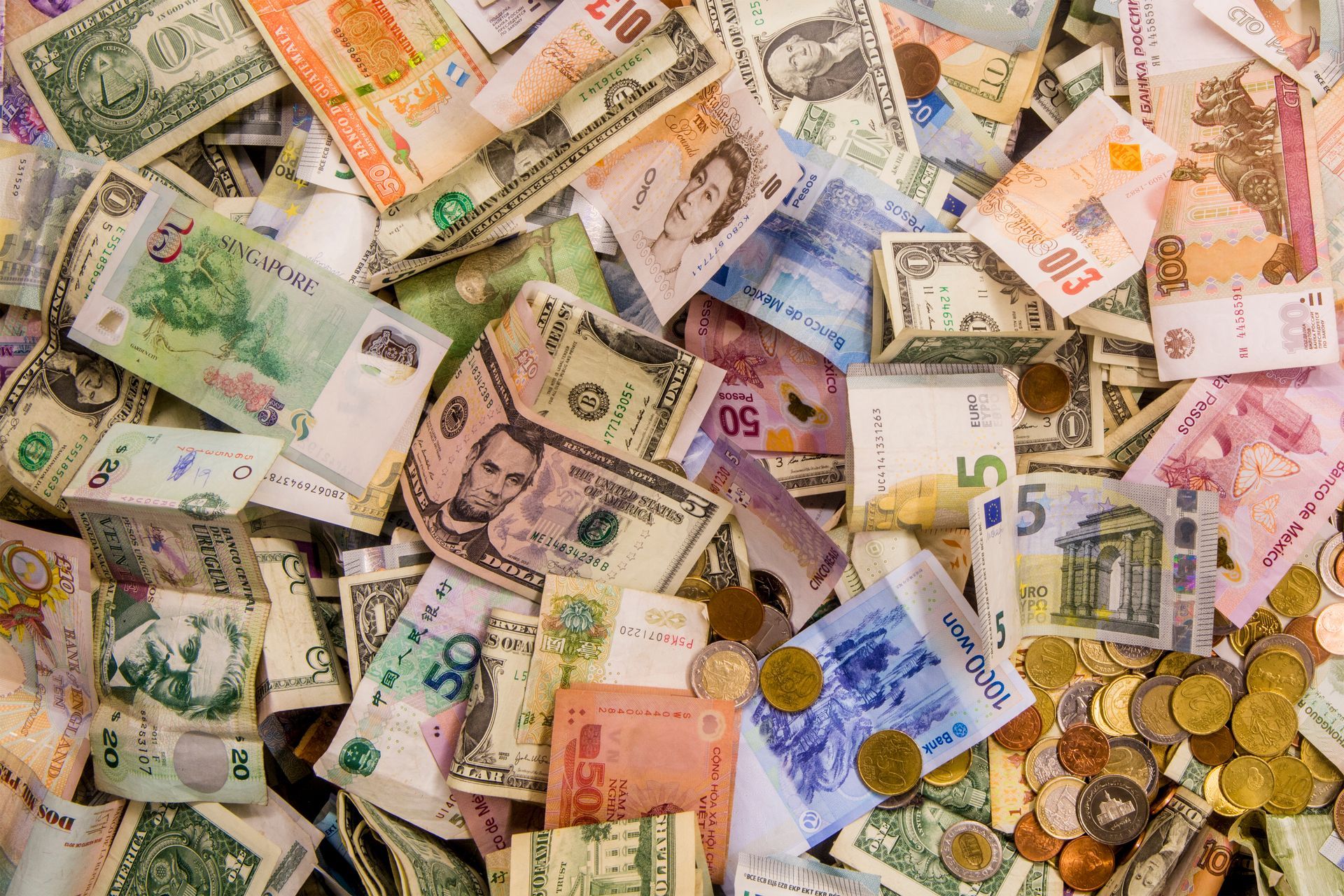 Pile de billets et de pièces de monnaie internationaux assortis.