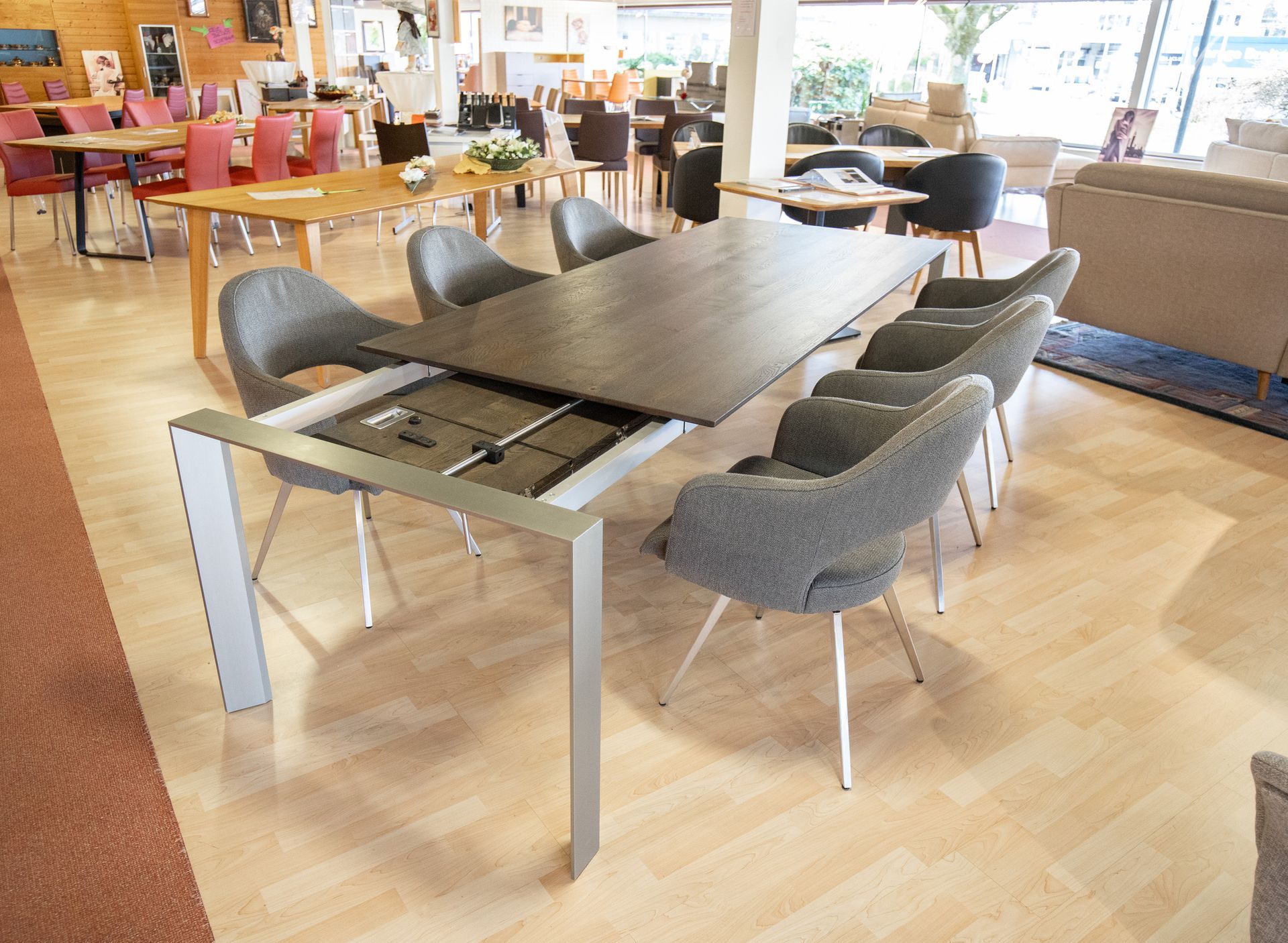 Ein Esstisch mit Stühlen und einer Couch im Hintergrund