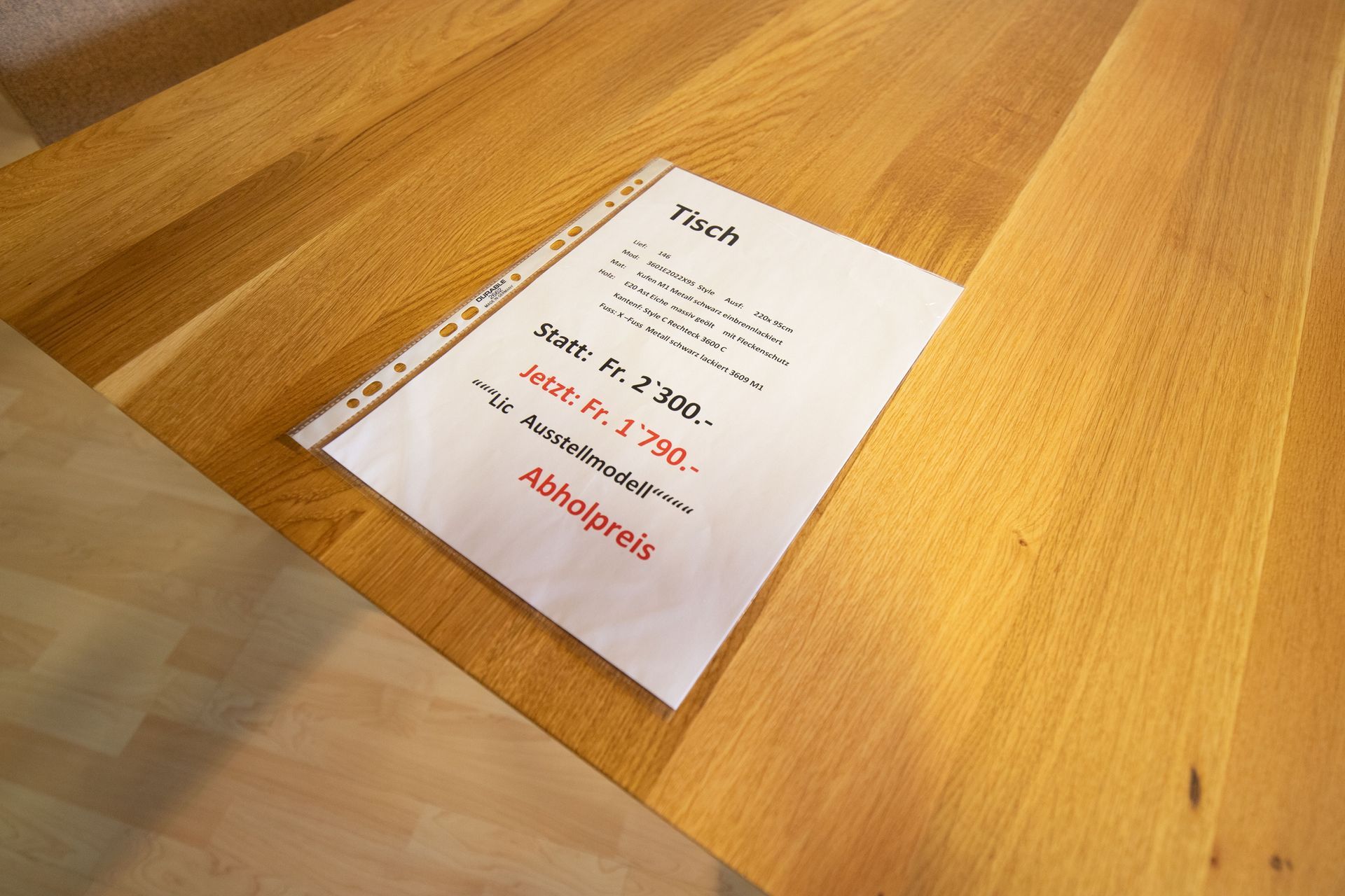 Auf einem Holztisch liegt ein Blatt Papier.