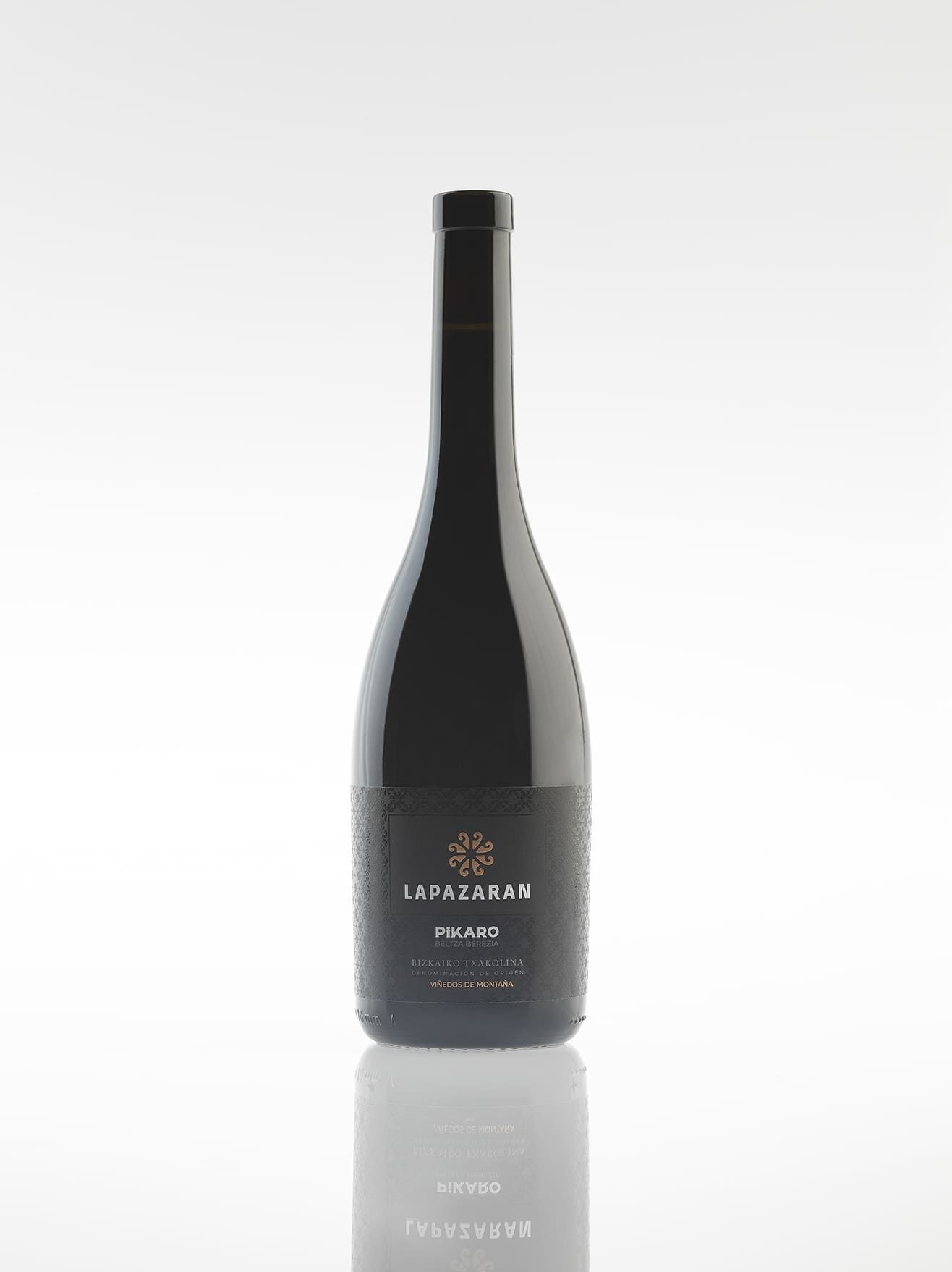 Botella de vino oscuro con etiqueta negra, superficie reflectante.