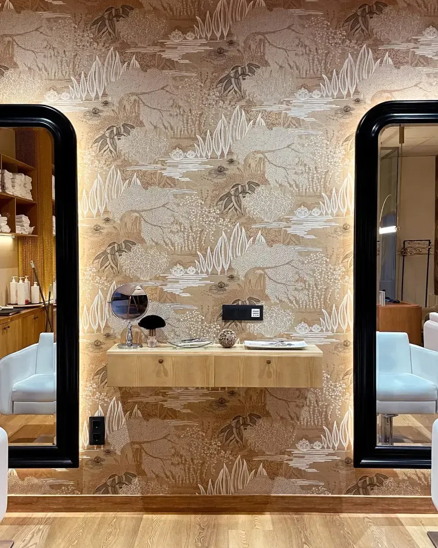 Un tocador con una pared con vetas de madera, flanqueado por espejos con marco negro. 