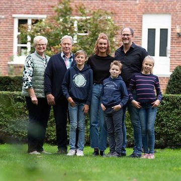 Eine Gruppe von Menschen posiert vor einem Backsteingebäude für ein Foto.