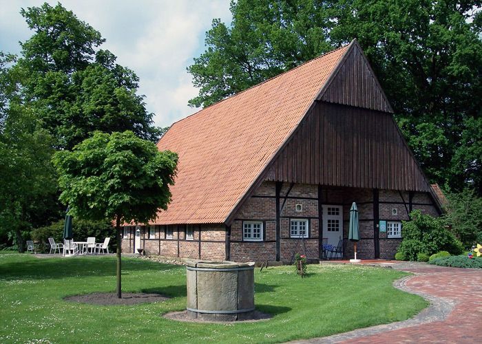 Eine große Scheune mit einem roten Ziegeldach liegt inmitten eines üppigen grünen Feldes