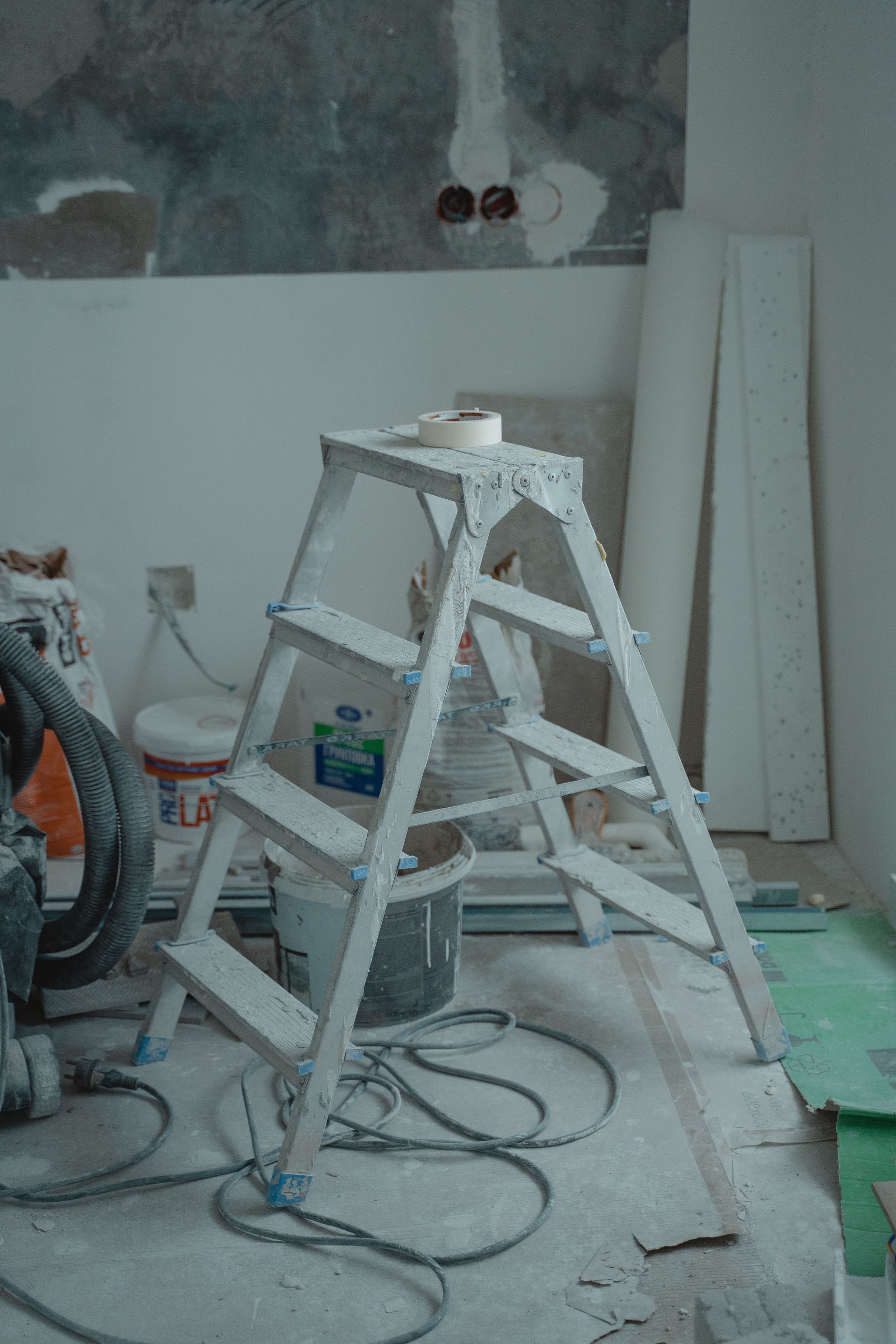 Cour en terre nue à côté d’une maison beige, bordée d’herbe et fermée au fond par un portail bleu.