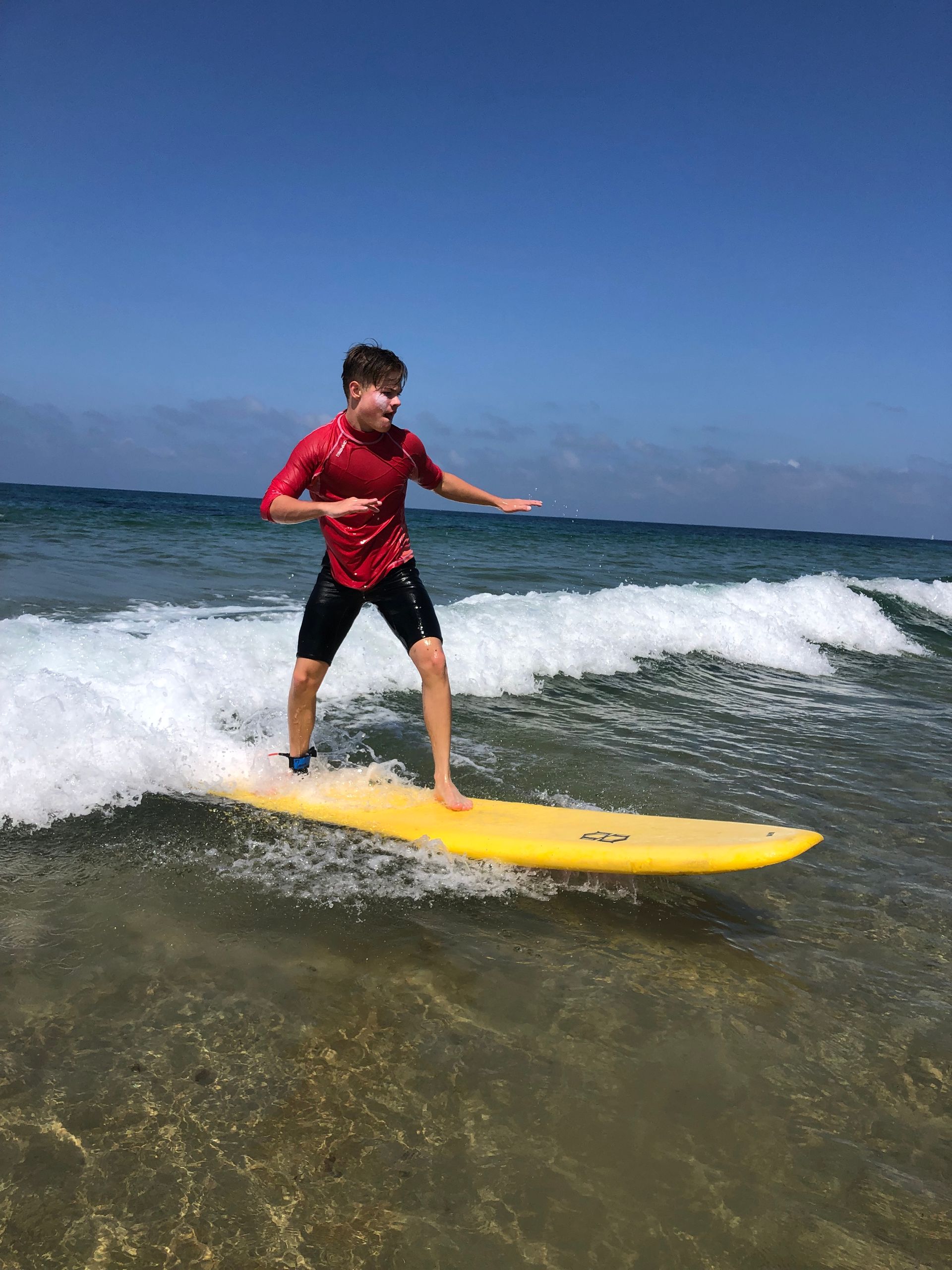 Adolescent debout sur sa planche de surf dans l'eau